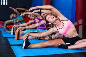 Smiling people doing stretching exercise in gym