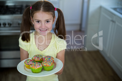 Girl holding a plate of cupcakes