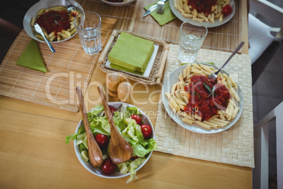 Plates of salad and pasta on dinning table