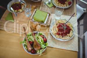 Plates of salad and pasta on dinning table