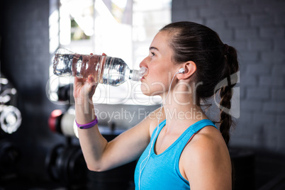 Female athlete drinking water in gym