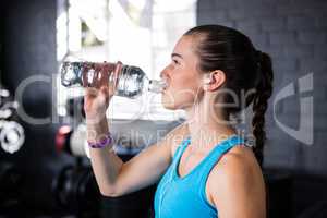 Female athlete drinking water in gym