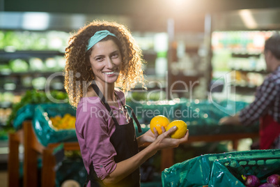 Smiling female staff holding fruits in organic section