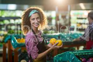 Smiling female staff holding fruits in organic section