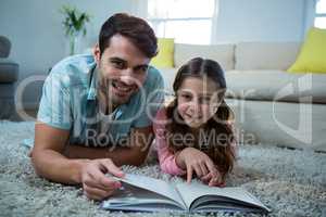 Father and daughter reading book in the living room