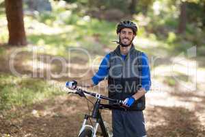 Male biker standing with mountain bike in forest