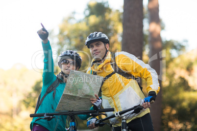 Biker couple with a map pointing in distance