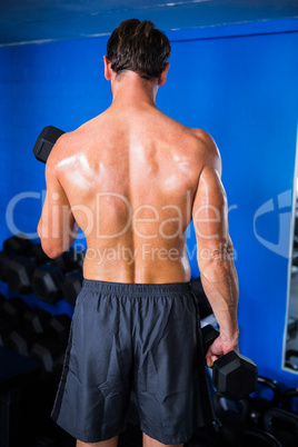 Rear view of athlete lifting dumbbell