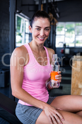 Smiling female athlete holding water bottle