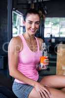 Smiling female athlete holding water bottle
