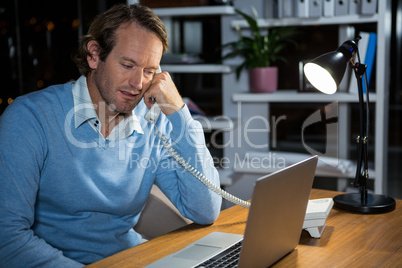 Businessman talking on phone while working in office