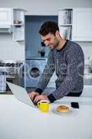 Man using laptop in the kitchen