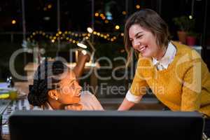 Businesswoman interacting with colleague looking at computer