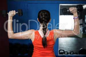 Rear view of young athlete lifting dumbbell