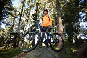 Female biker standing with mountain bike in forest