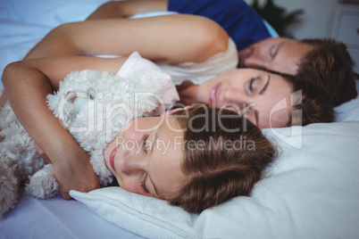 Family sleeping on bed