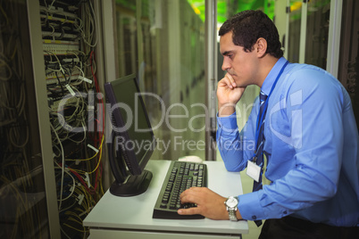 Technician working on personal computer while analyzing server