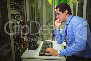 Technician working on personal computer while analyzing server