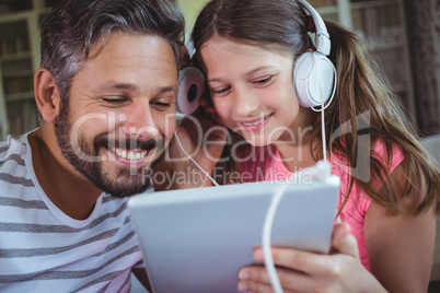 Father and daughter listening music on digital tablet