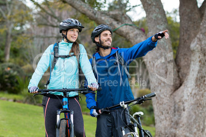 Biker couple with mountain bike pointing in distance