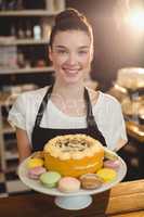 Portrait of waitress holding dessert on cake stand