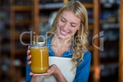 Female staff holding jar of honey in supermarket