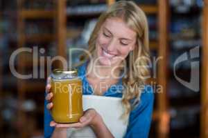 Female staff holding jar of honey in supermarket