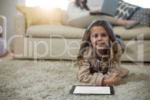 Girl using digital tablet while lying on the floor