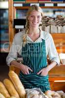 Smiling female staff standing at bread counter