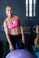 Smiling female athlete standing by exercise ball