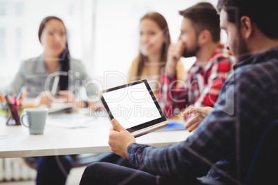 Colleague using digital tablet against photo editors