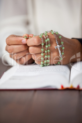 Praying hands of woman with a rosary on bible