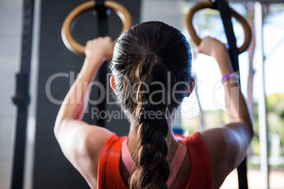 Rear view of female athlete holding gymnastic rings