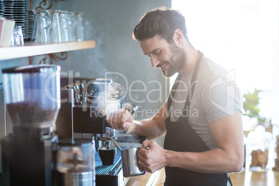 Smiling waiter making cup of coffee