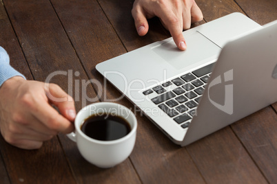 Man using laptop while having cup of coffee Man using laptop while having cup of coffee