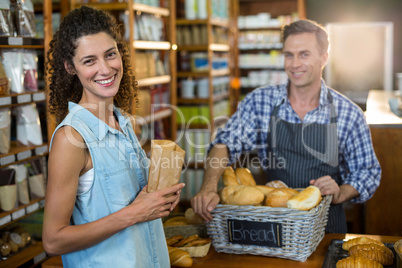 Portrait of smiling woman purchasing bread at bakery store