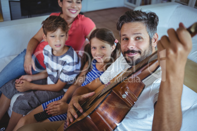 Happy family sitting on sofa with a guitar