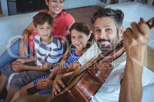 Happy family sitting on sofa with a guitar