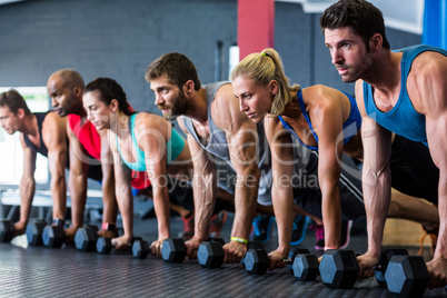 People doing push-ups with dumbbell in gym