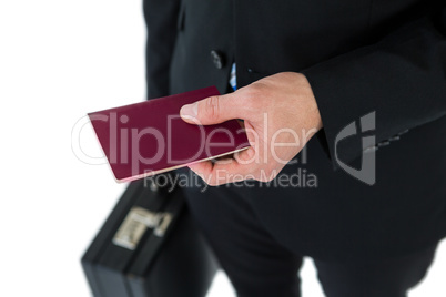 Mid section of businessman holding briefcase and passport