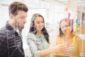 Coworkers looking at sticky notes pointed by female photo editor