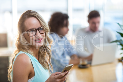 Smiling woman using mobile phone in cafÃ?Â©