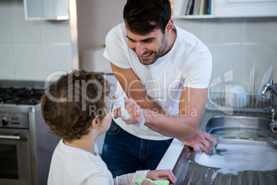 Son helping father in washing utensils