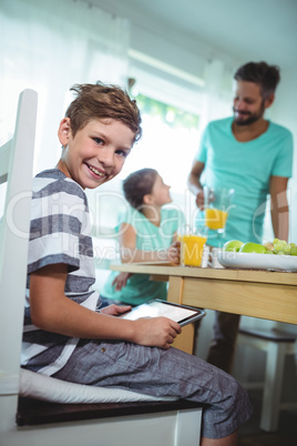 Boy using digital tablet with breakfast on table