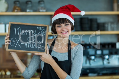 Portrait of waitress showing slate with merry x-mas sign