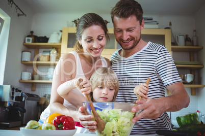 Parents watching their daughter mixing the salad