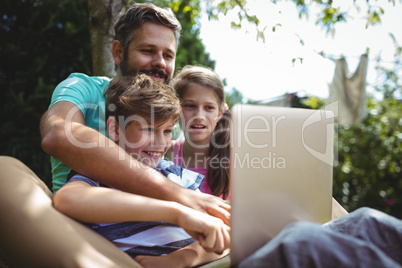 Father and kids using laptop in garden