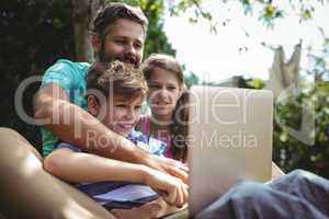 Father and kids using laptop in garden