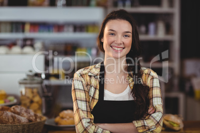 Portrait of smiling waitress standing with arms crossed