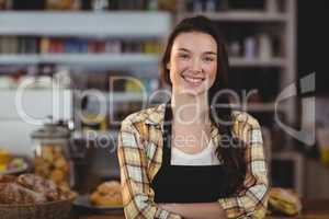 Portrait of smiling waitress standing with arms crossed